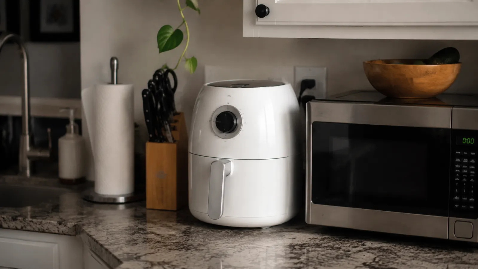 Small air fryer on a cramped apartment counter next to a microwave, showing how little space it takes