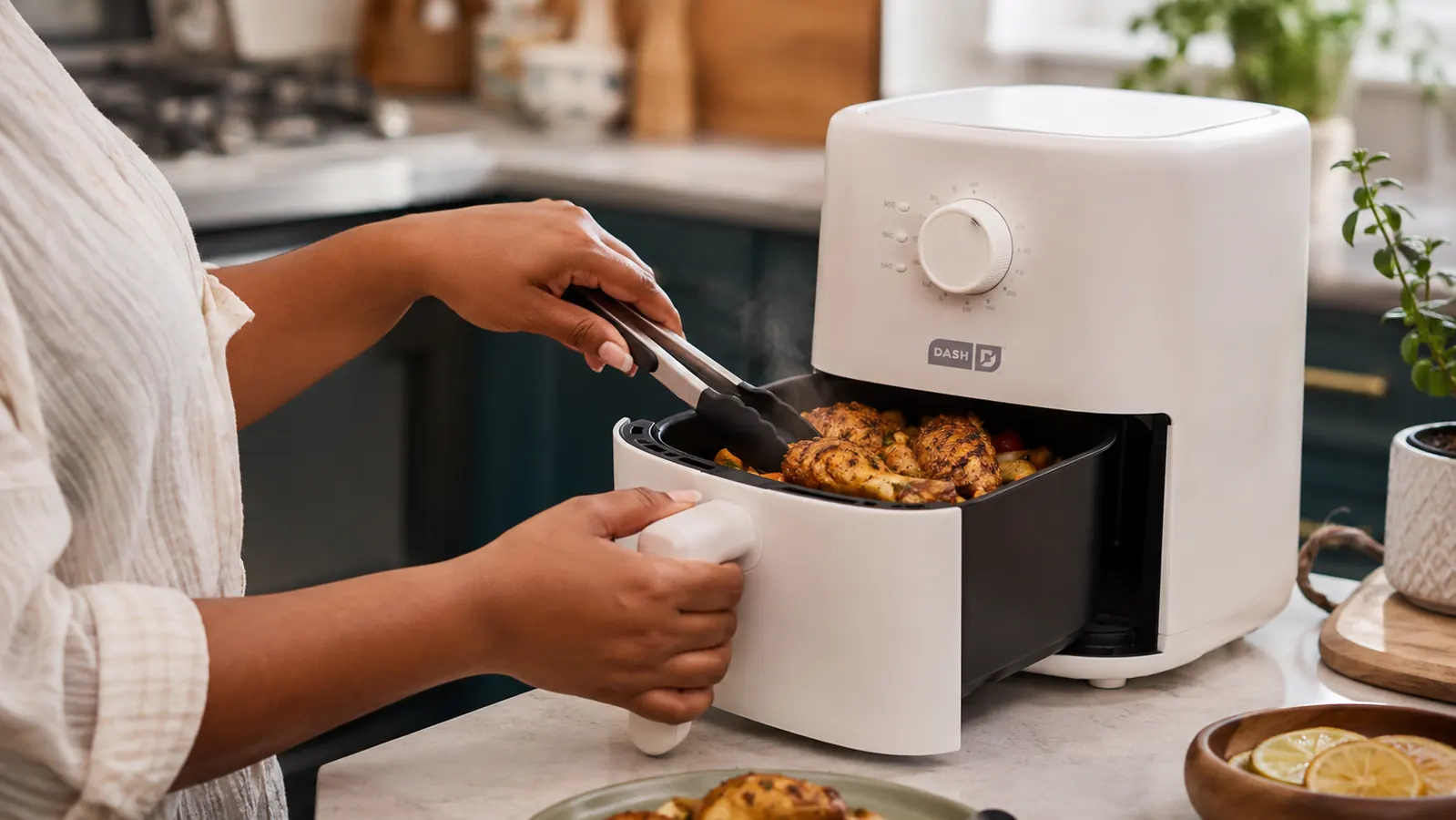 Small white air fryer basket partially pulled out to flip food halfway through cooking